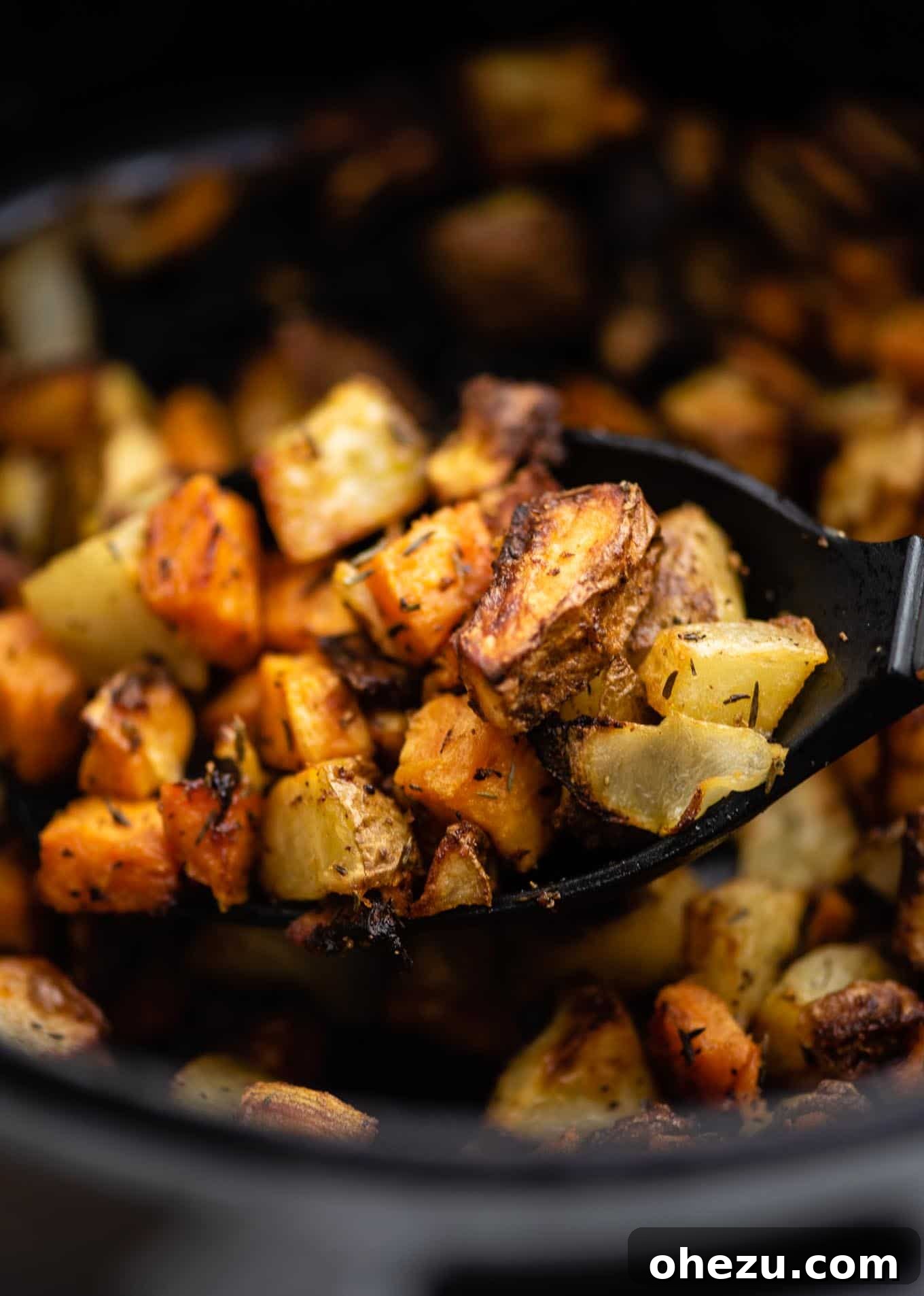 A scoop of crispy potatoes and onions on a serving spoon.