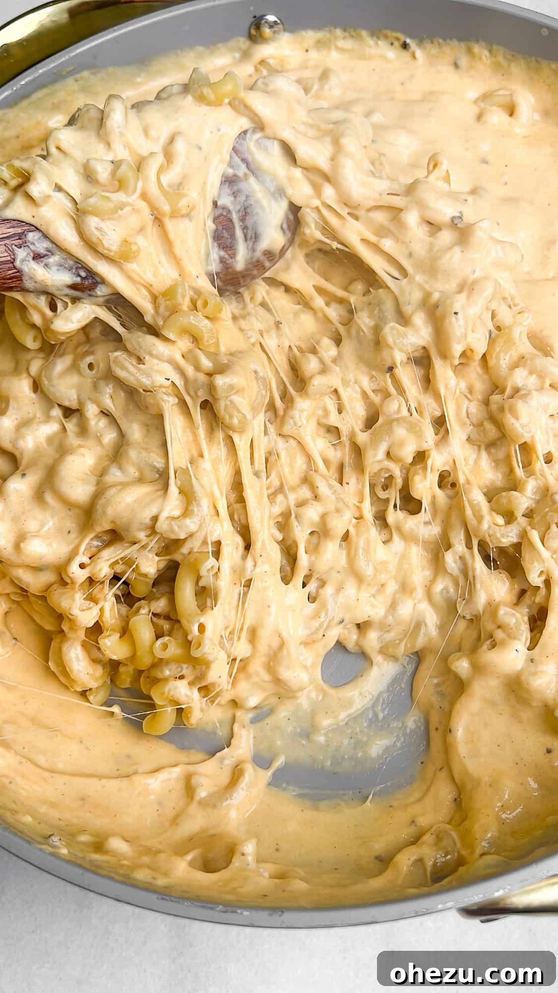 Macaroni and cheese sauce thoroughly mixed together in a pan, ensuring every piece is coated.