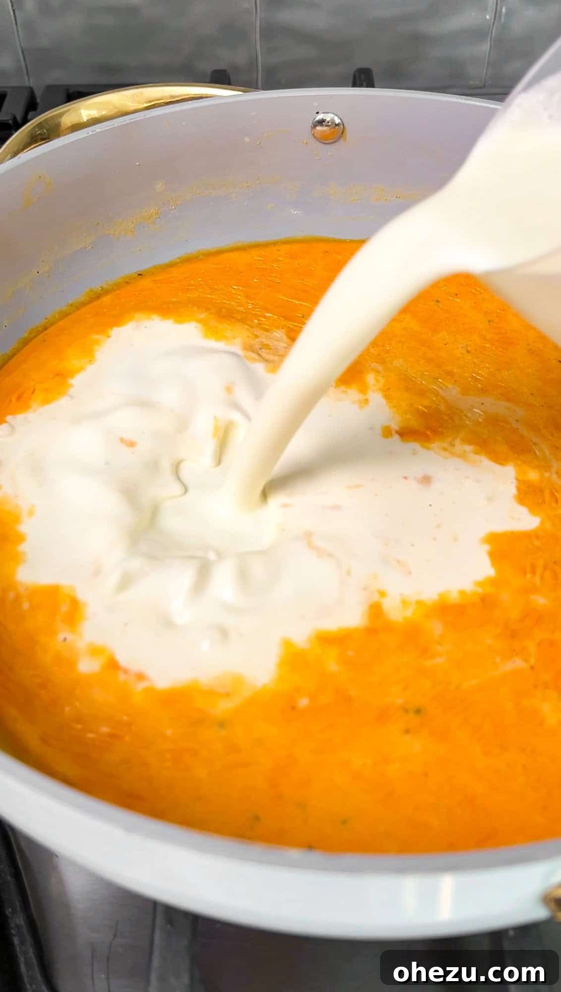 Step 3: Evaporated milk and cream being poured into the roux to form the sauce base.