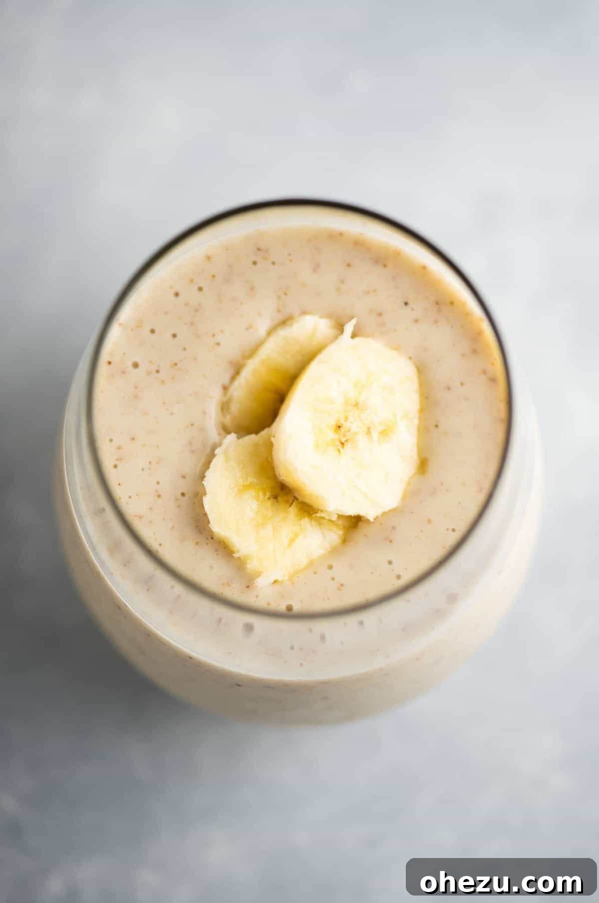Banana Bliss 2 A perfectly blended banana smoothie in a clear glass, garnished with fresh banana slices on top, ready to be enjoyed.
