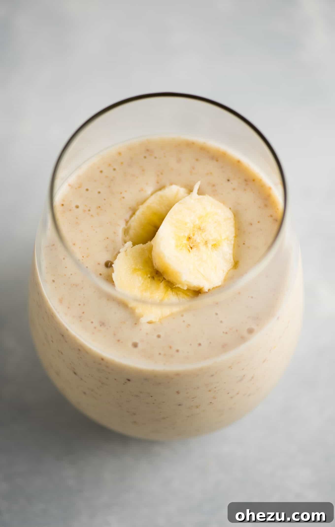 Banana Bliss 5 A beautifully presented banana smoothie in a glass, captured with a soft background blur, emphasizing its tempting and creamy texture.