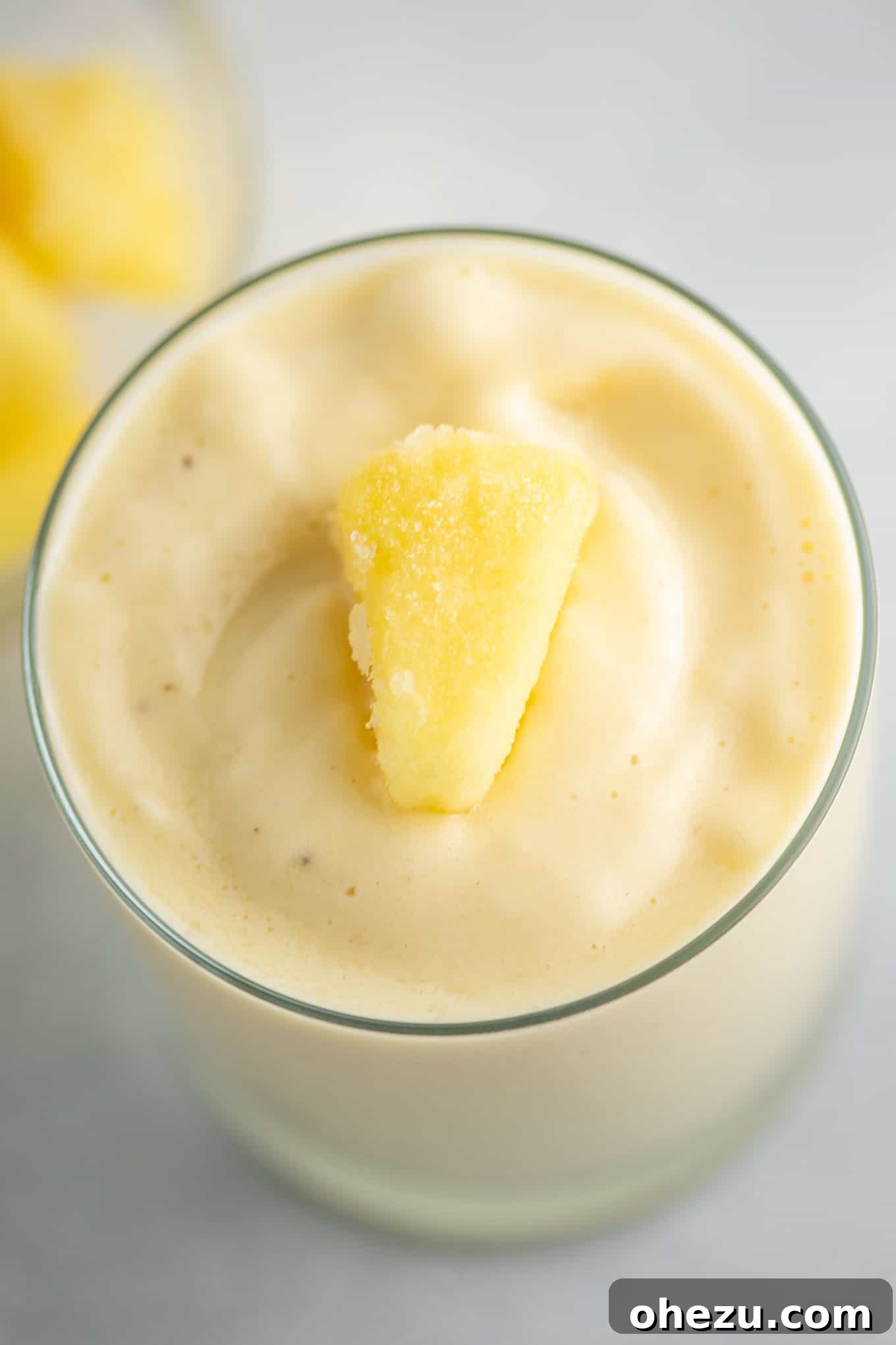 Golden Pineapple Chill 3 Close-up shot of the frosty pineapple smoothie, topped with glistening frozen pineapple chunks, emphasizing its thick and cold texture.
