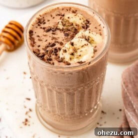 chocolate peanut butter banana smoothie topped with chocolate shavings and banana slices