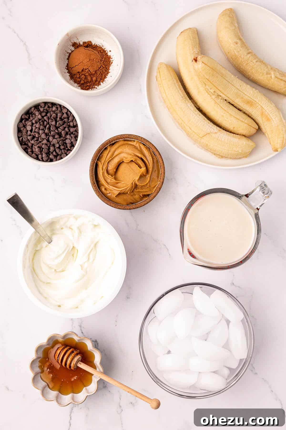 Assortment of fresh and frozen ingredients for a chocolate peanut butter banana smoothie laid out on a surface.
