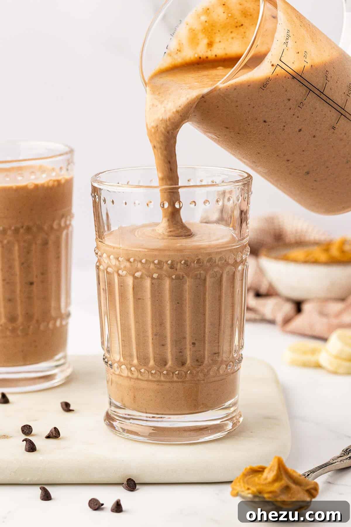 Pouring the blended chocolate peanut butter banana smoothie into a glass.