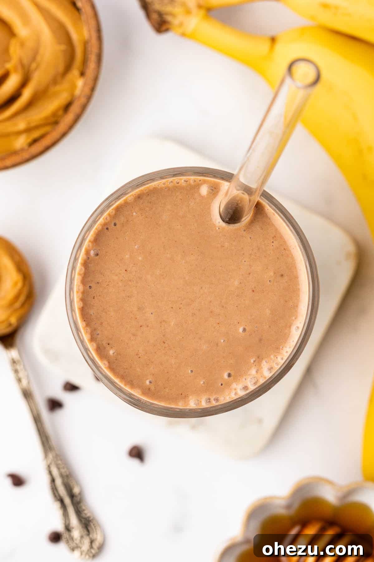 A finished chocolate peanut butter banana smoothie in a glass with a straw, garnished minimally.