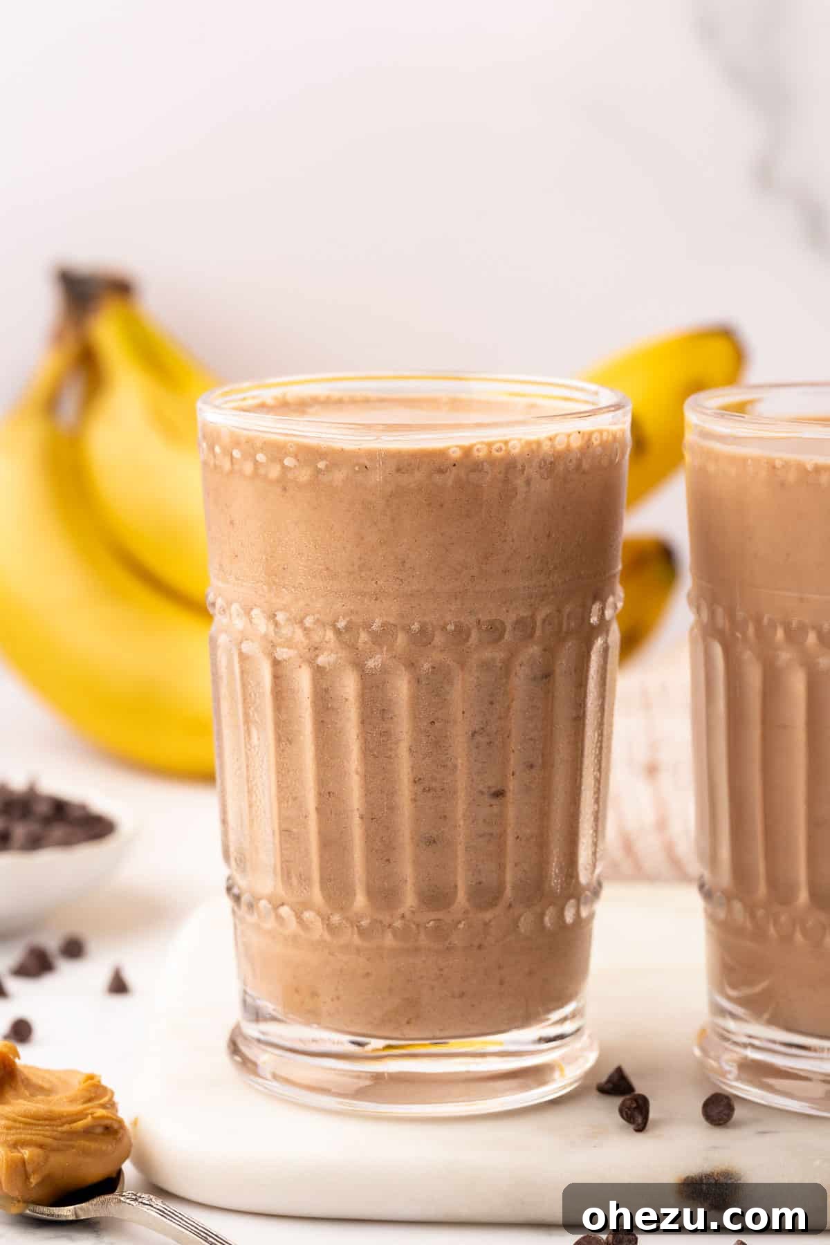 A close-up of a chocolate peanut butter banana smoothie in a glass, showcasing its rich texture and color.