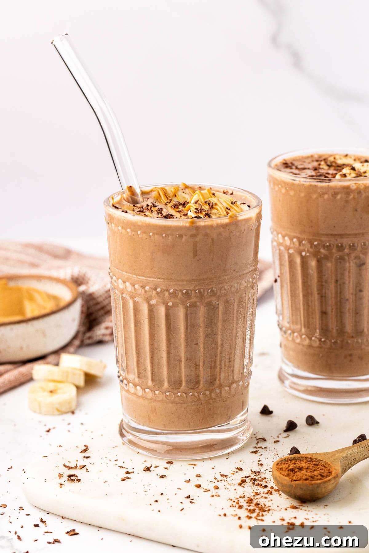 Another view of the chocolate peanut butter banana smoothie in a glass with a straw, ready to drink.