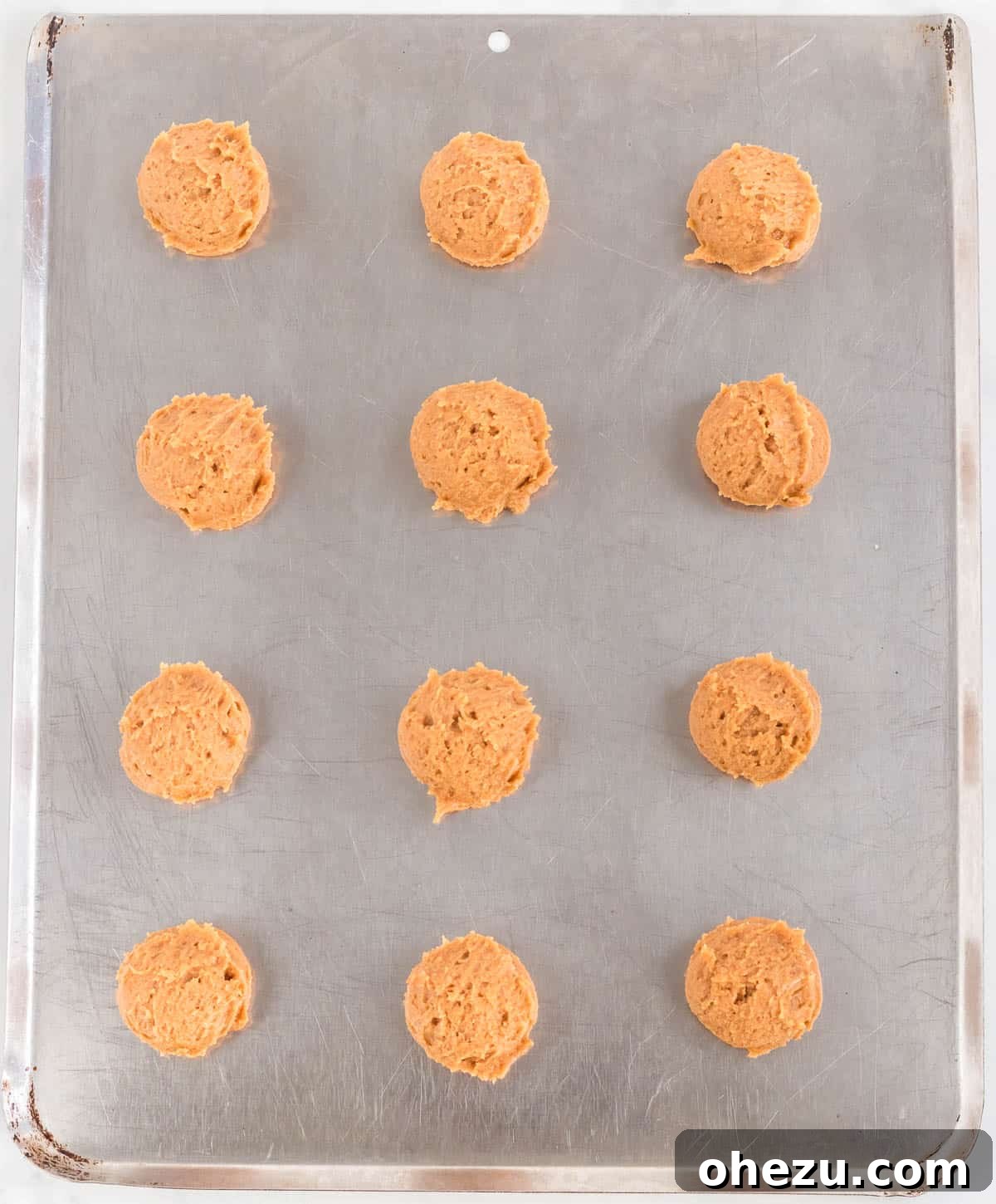 Gluten-Free Peanut Butter Cookies 6 Balls of gluten-free cookie dough neatly arranged on a baking sheet before baking
