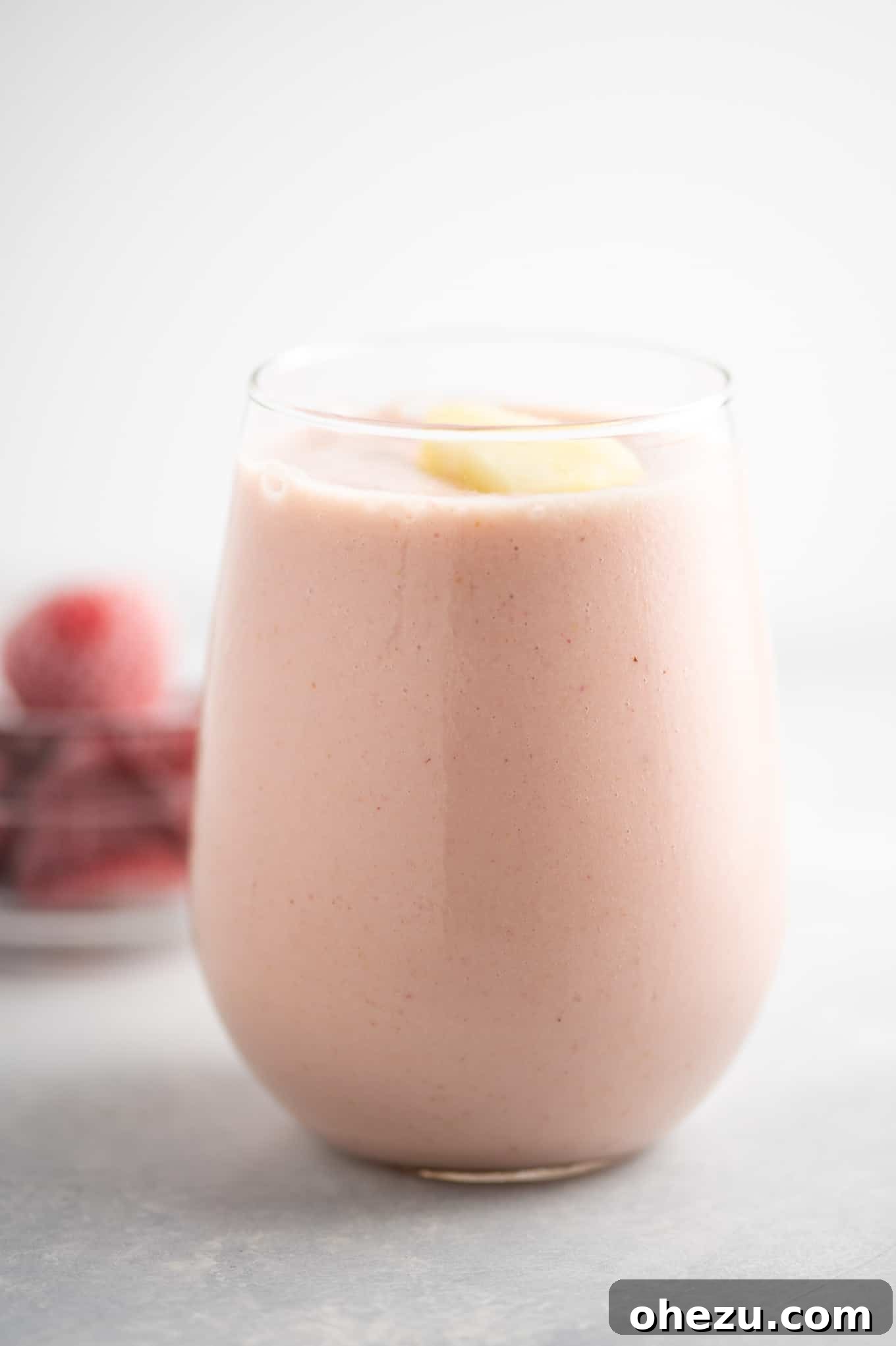 Strawberry Pineapple Paradise 3 Close-up of a refreshing strawberry pineapple smoothie with frozen fruit in the background