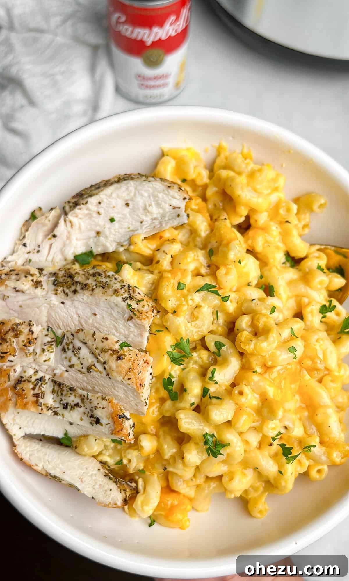 A generous serving of creamy slow cooker mac and cheese on a white plate, accompanied by slices of roasted chicken, highlighting a perfect meal pairing.