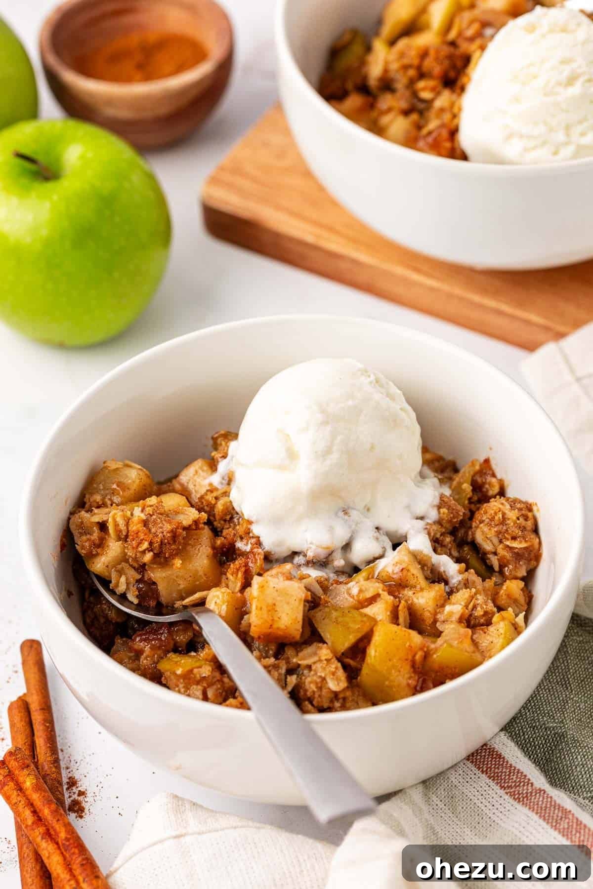 Heavenly Gluten-Free Apple Crumble 14 A serving of gluten-free apple crisp in a bowl, generously topped with a scoop of vanilla ice cream that has just begun to melt, creating a delightful creamy pool.