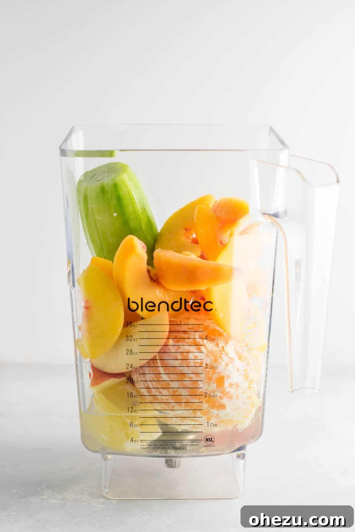 Mastering Homemade Smoothies 6 a blender filled with an assortment of fresh ingredients including cucumber, lemon, apples, oranges, peaches, and water, ready to be blended into a healthy smoothie