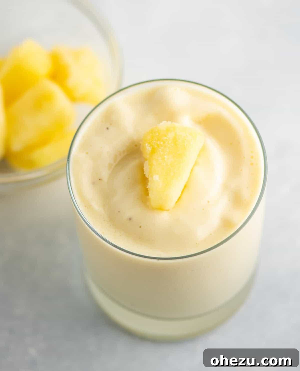 Mastering Homemade Smoothies 7 a vibrant pineapple smoothie served in a clear glass, topped with a piece of frozen pineapple