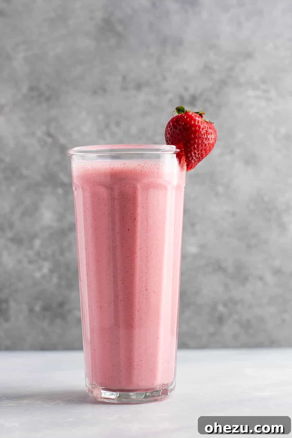 Mastering Homemade Smoothies 10 a vibrant strawberry smoothie in a tall glass, adorned with a fresh strawberry on the rim, showcasing its thick and frosty texture