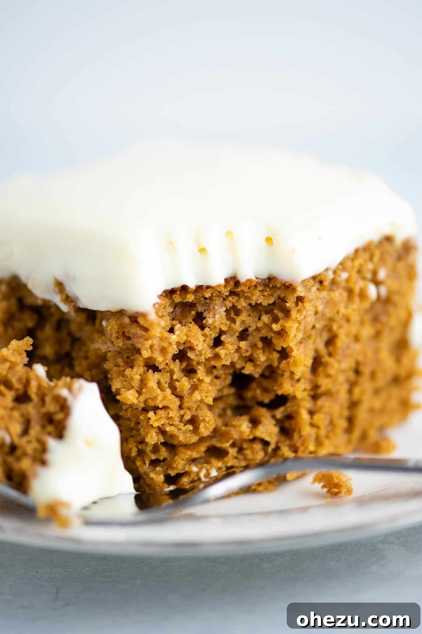 A charming image of a fully frosted pumpkin cake in a baking dish, with a slice removed, showing its inviting texture and ready to be served.