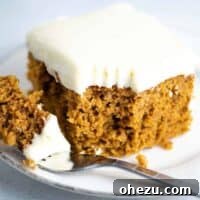Pumpkin cake recipe with cream cheese frosting slice with a bite taken out on a fork
