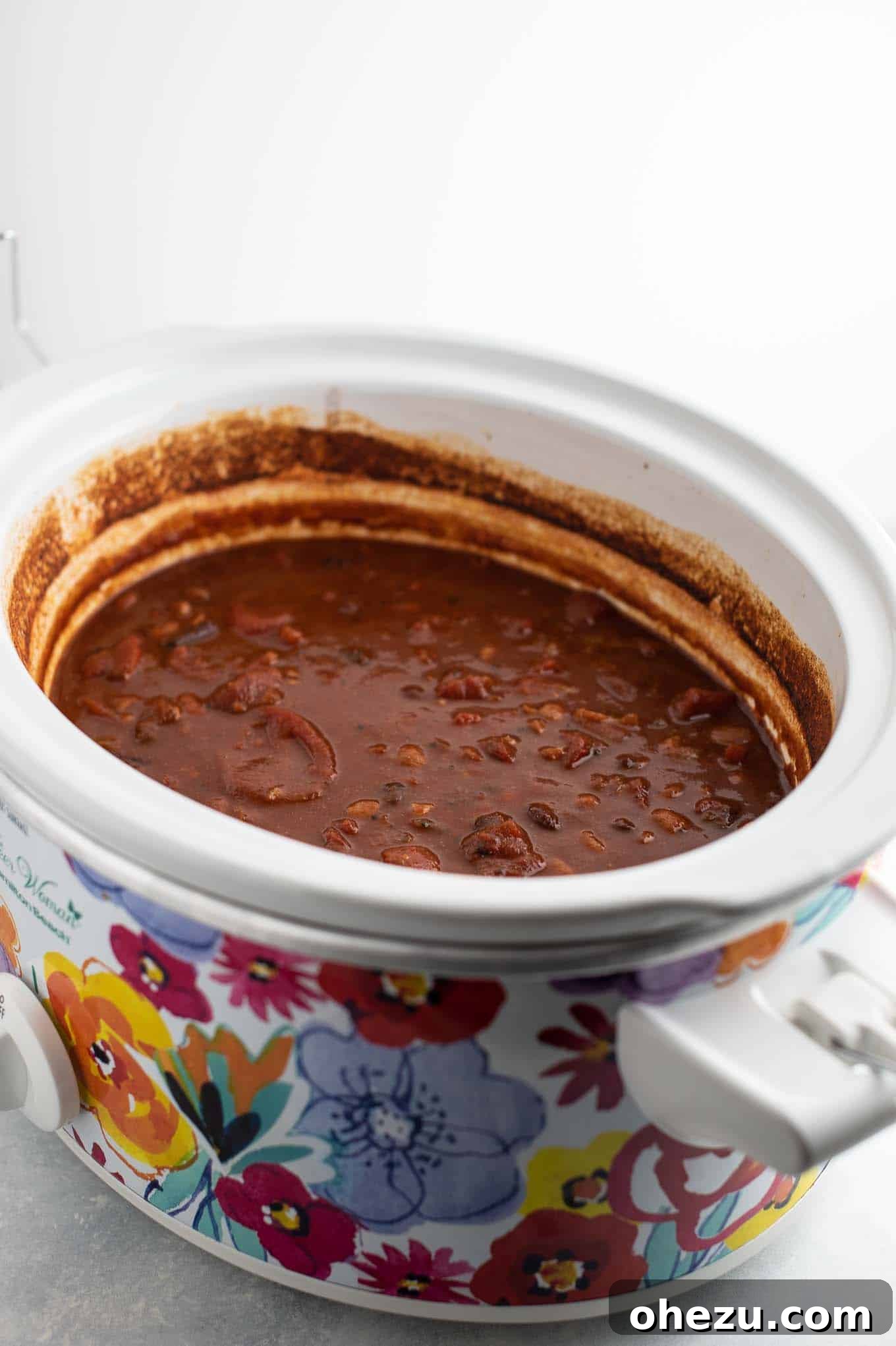 A floral Pioneer Woman brand crock pot filled with simmering vegetarian chili, ready for serving.