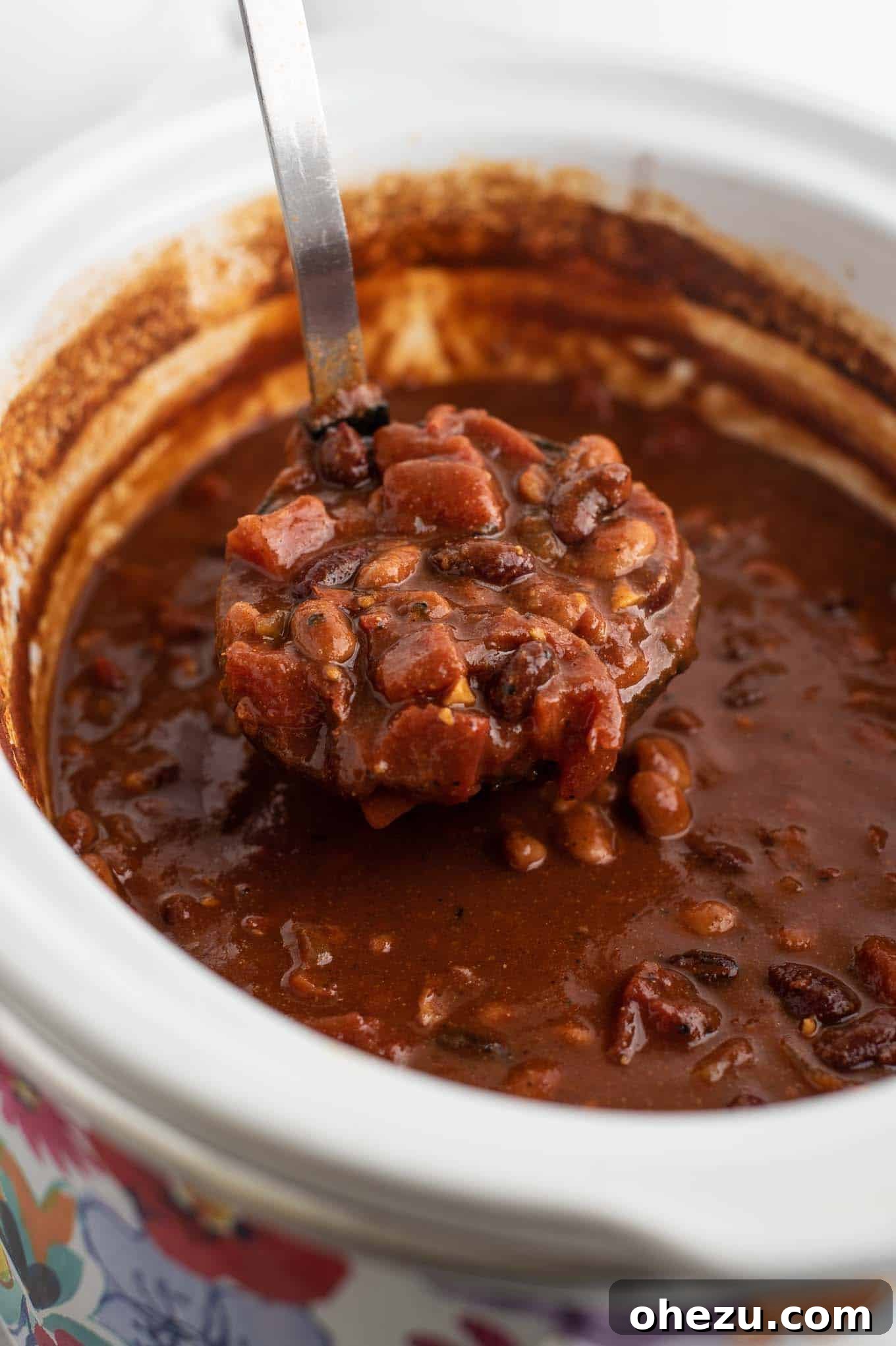 A ladle filled with rich, thick vegan chili, showcasing its hearty texture.