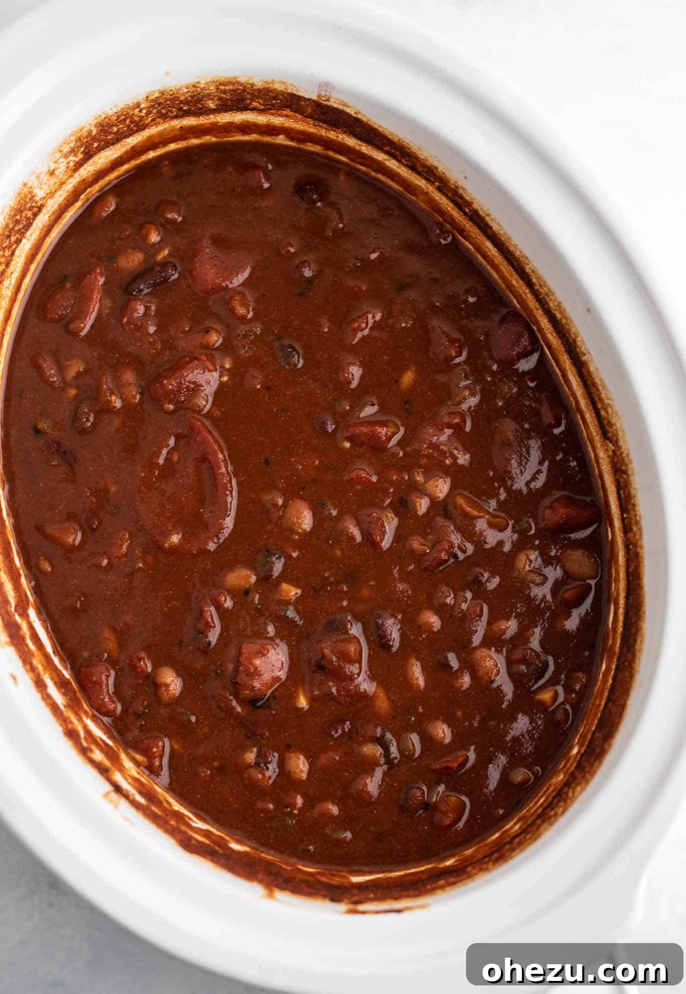 An overhead view of a crock pot brimmed with hearty, slow-cooked chili, ready to be served.