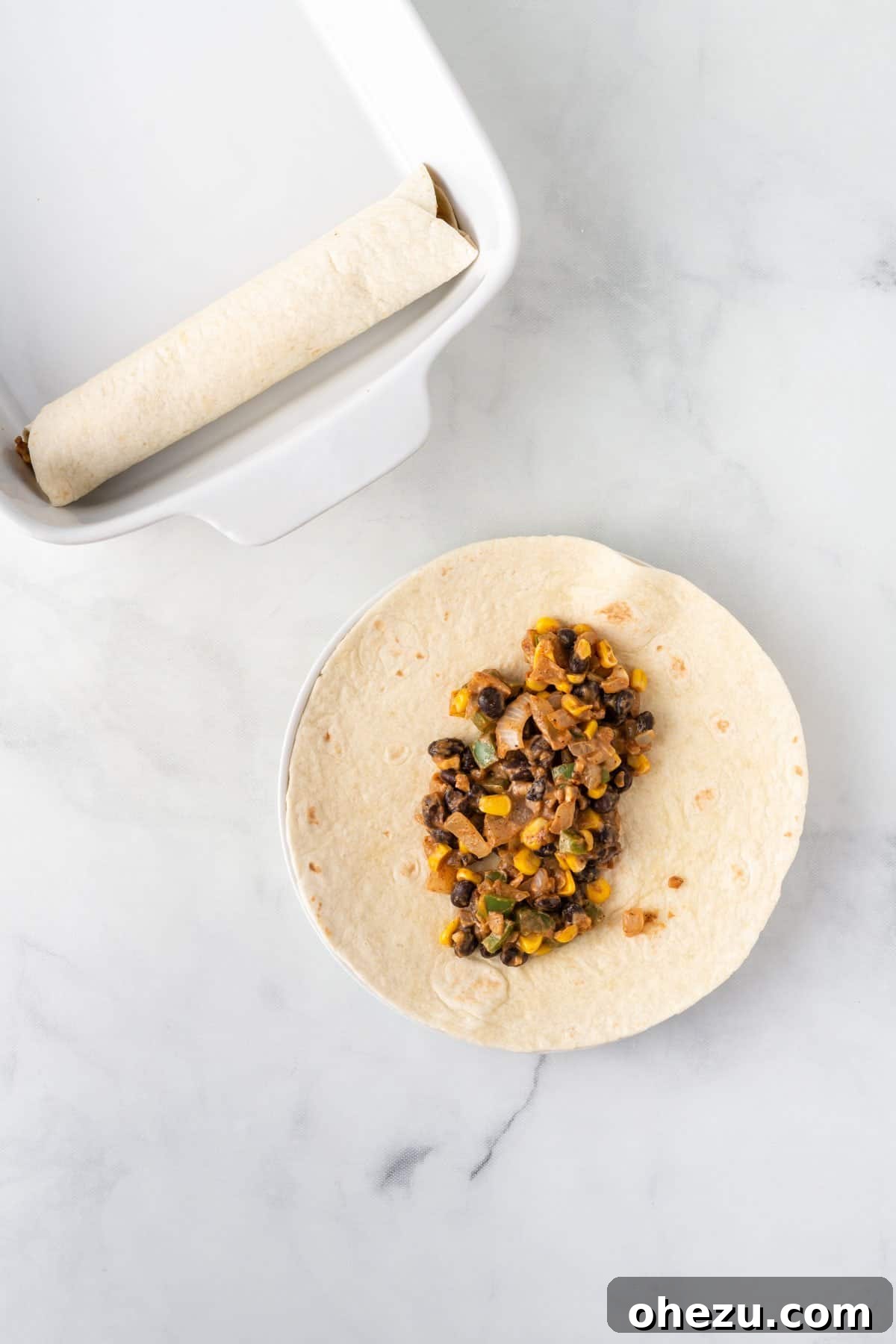 Adding a generous amount of creamy vegetarian filling to the center of a soft flour tortilla, ready for rolling.