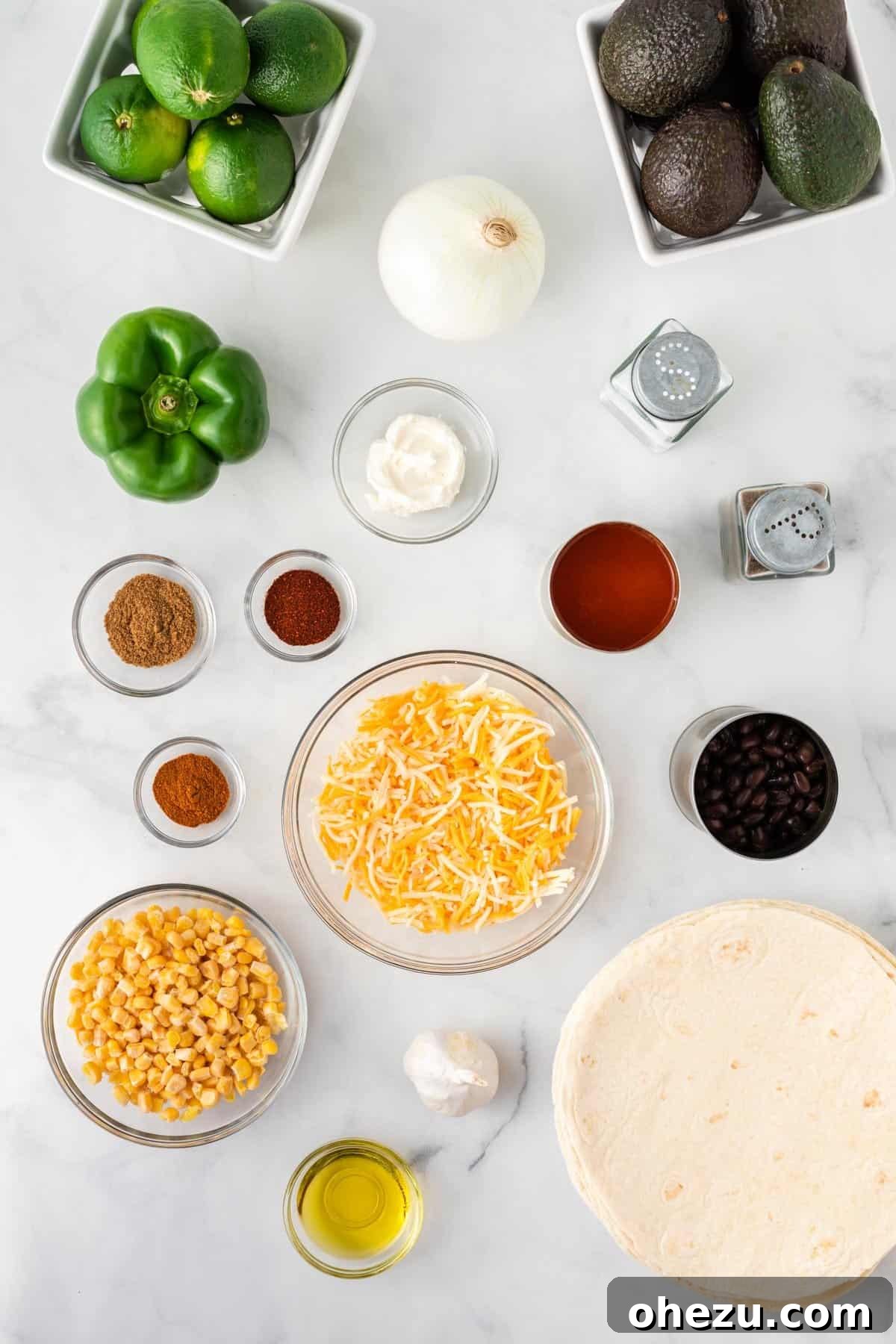 An assortment of fresh ingredients laid out on a kitchen counter, including onions, bell peppers, corn, spices, and cheese, all ready for making delicious vegetarian enchiladas.