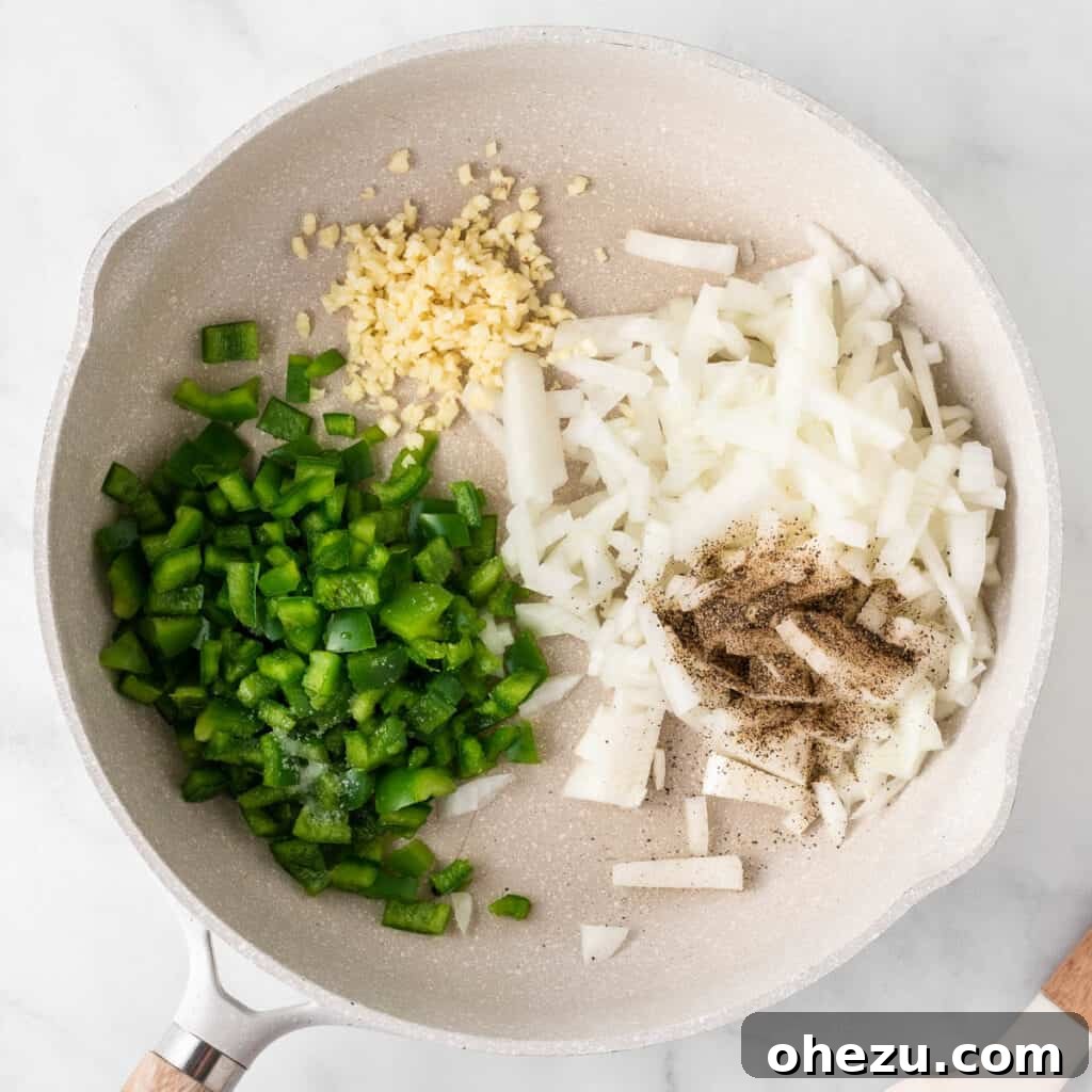 Diced onion, minced garlic, and green bell pepper cooking in olive oil in a skillet, gently sautéing.