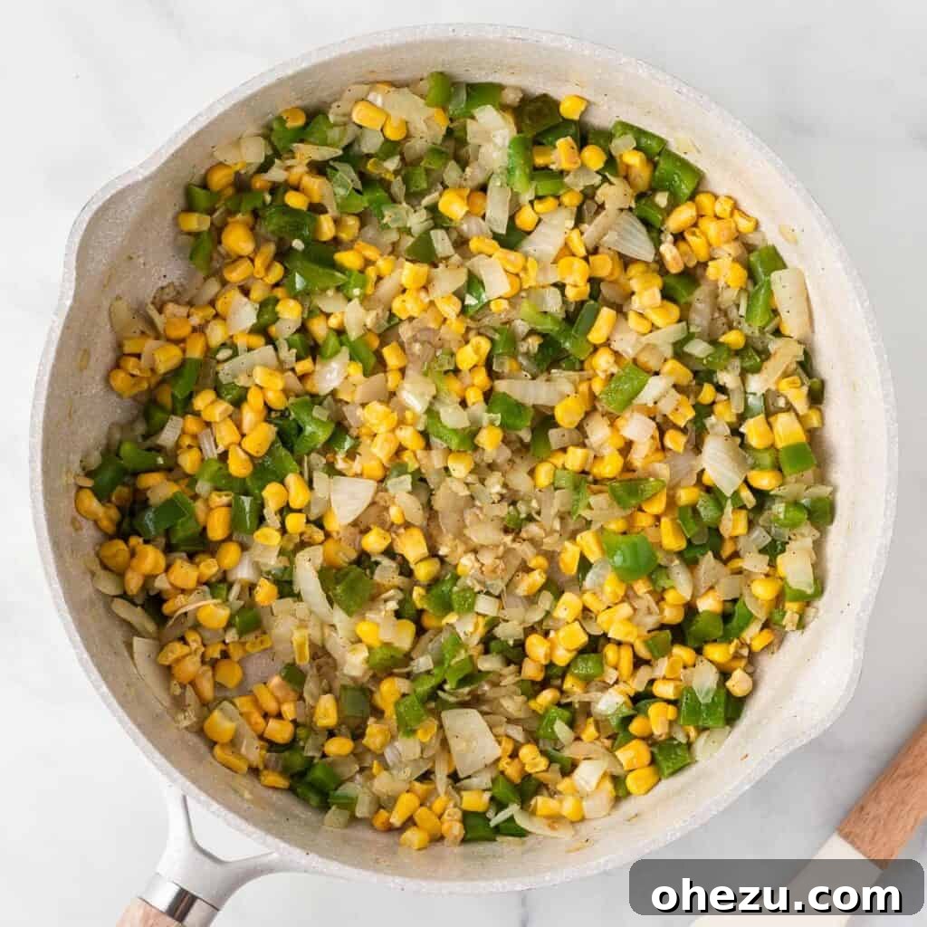 Vegetable filling mixture, including corn, cooking and warming through in a skillet, creating a vibrant base.