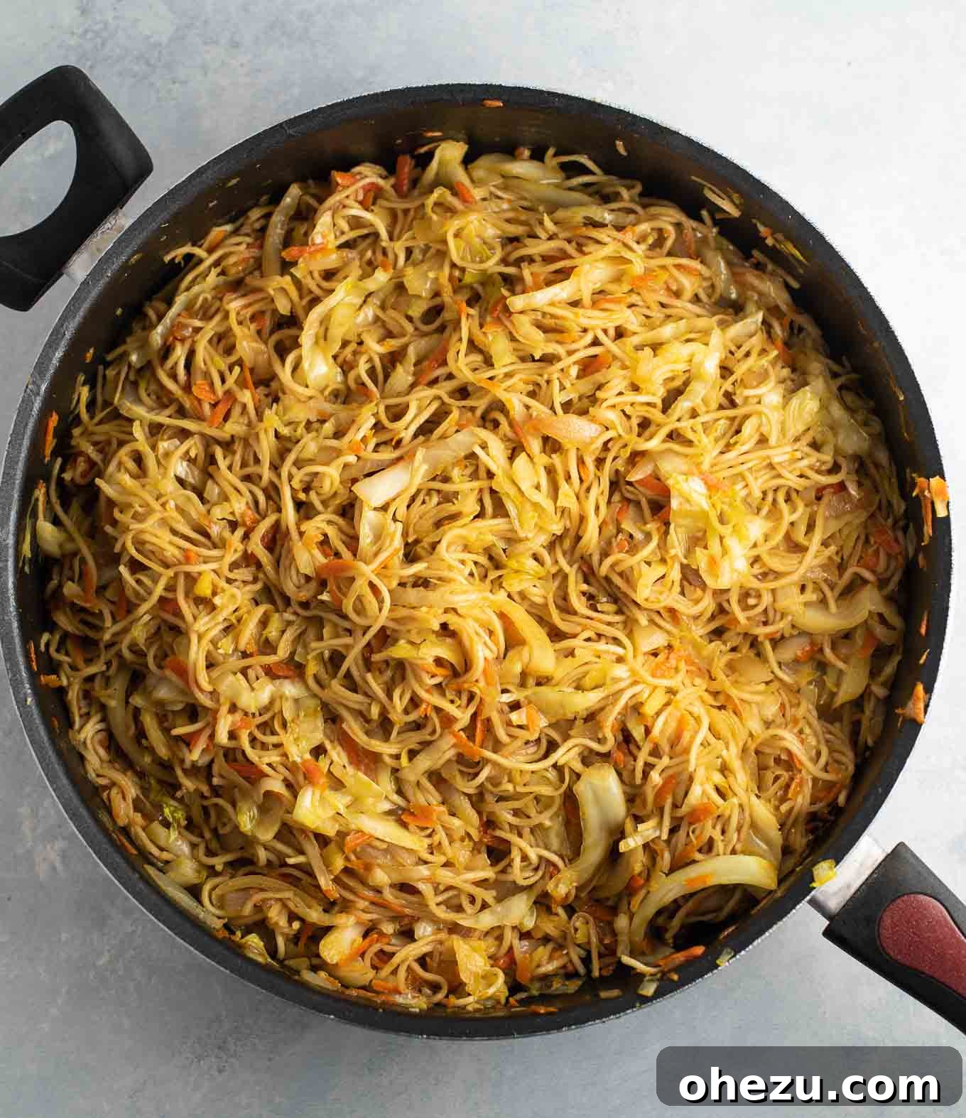 An inviting overhead view of a large skillet filled with perfectly cooked cabbage stir fry noodles, ready to be served.