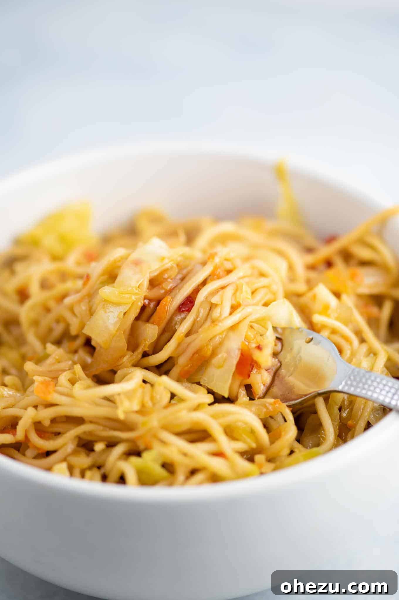 A close-up shot of the stir fry in a bowl, with a fork twirled around a perfect bite of noodles and vegetables.