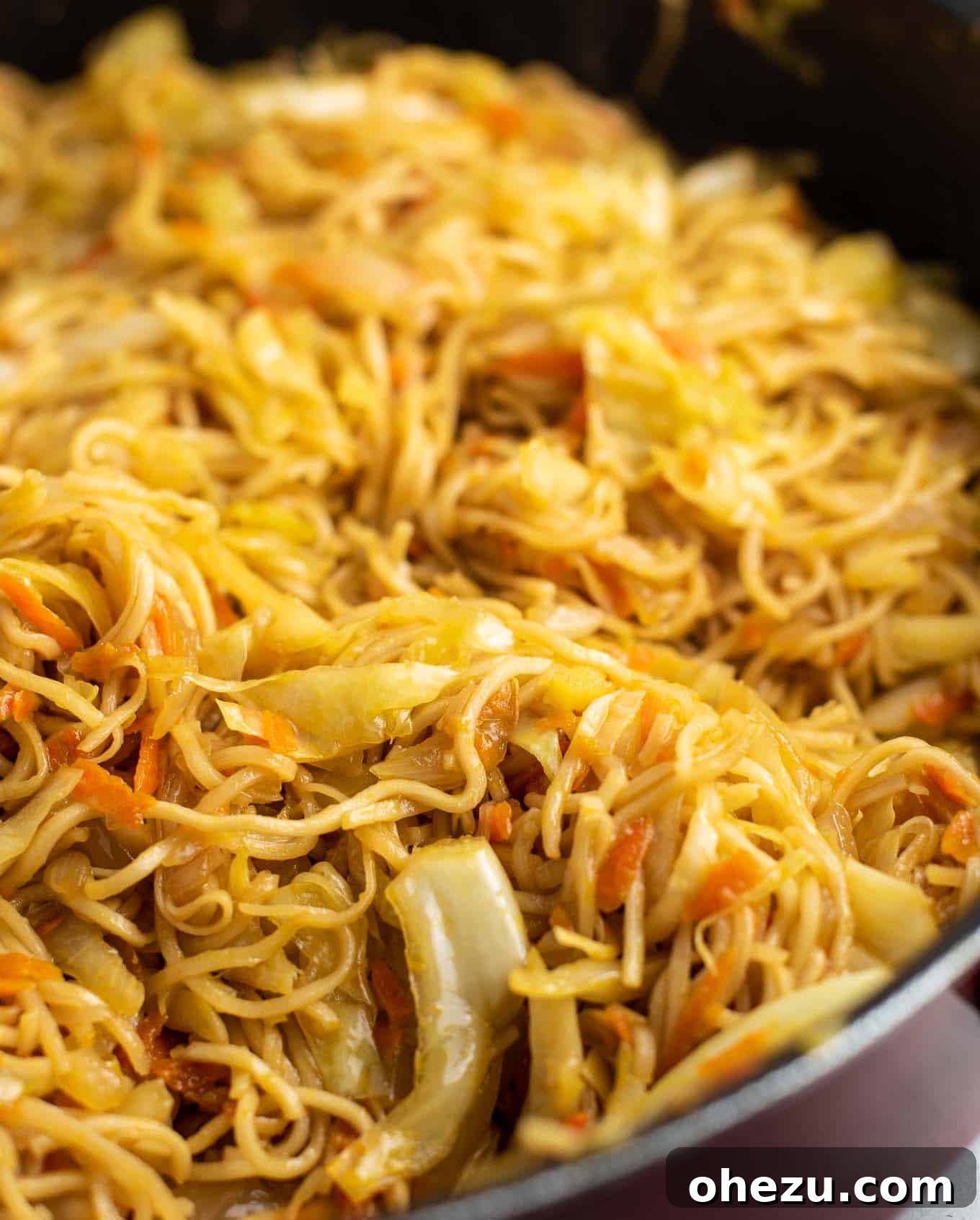 Freshly sliced cabbage and grated carrots mingling with cooked ramen noodles, ready for the sauce.