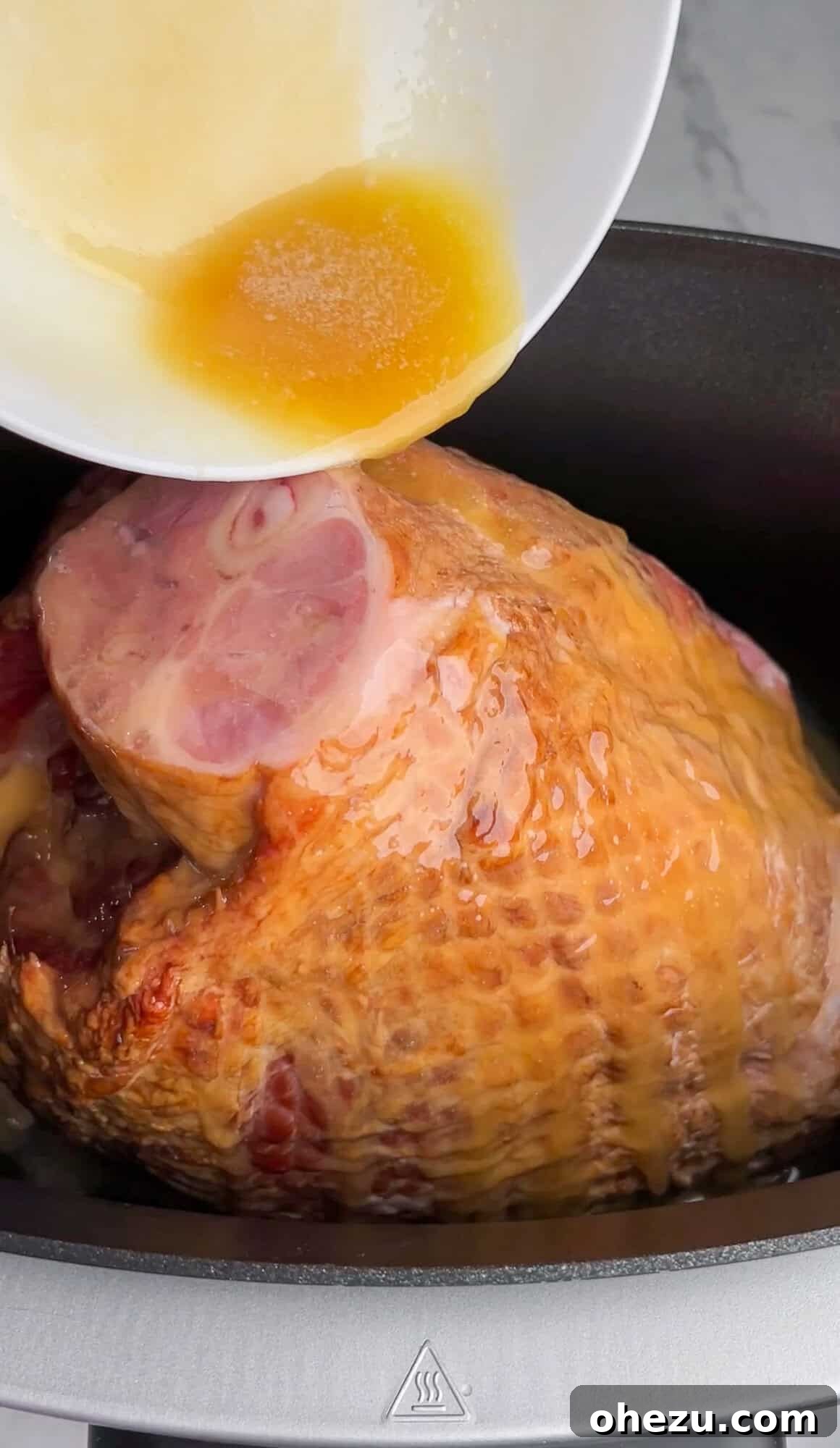 Tender Honey Glazed Slow Cooker Ham 5 butter and honey being poured over the ham in a slow cooker