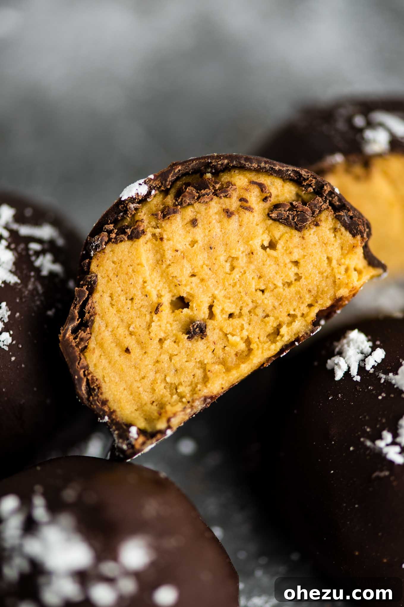 Pumpkin truffle cut in half to show the creamy cheesecake filling and crunchy graham cracker base