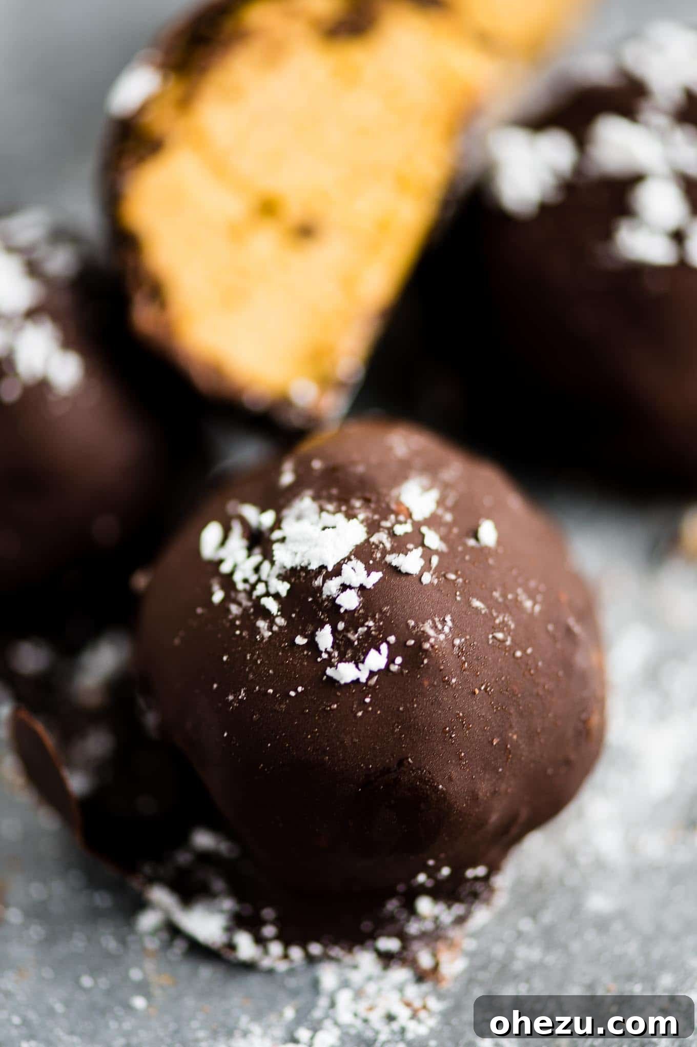Pumpkin cheesecake truffles sprinkled with powdered sugar on a white surface