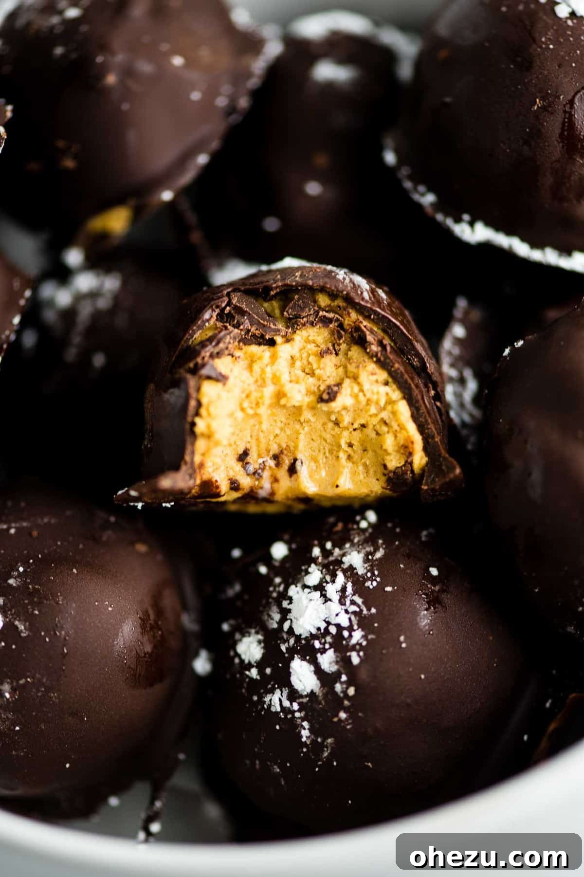Dark chocolate pumpkin truffle with a bite taken out, showing the rich filling