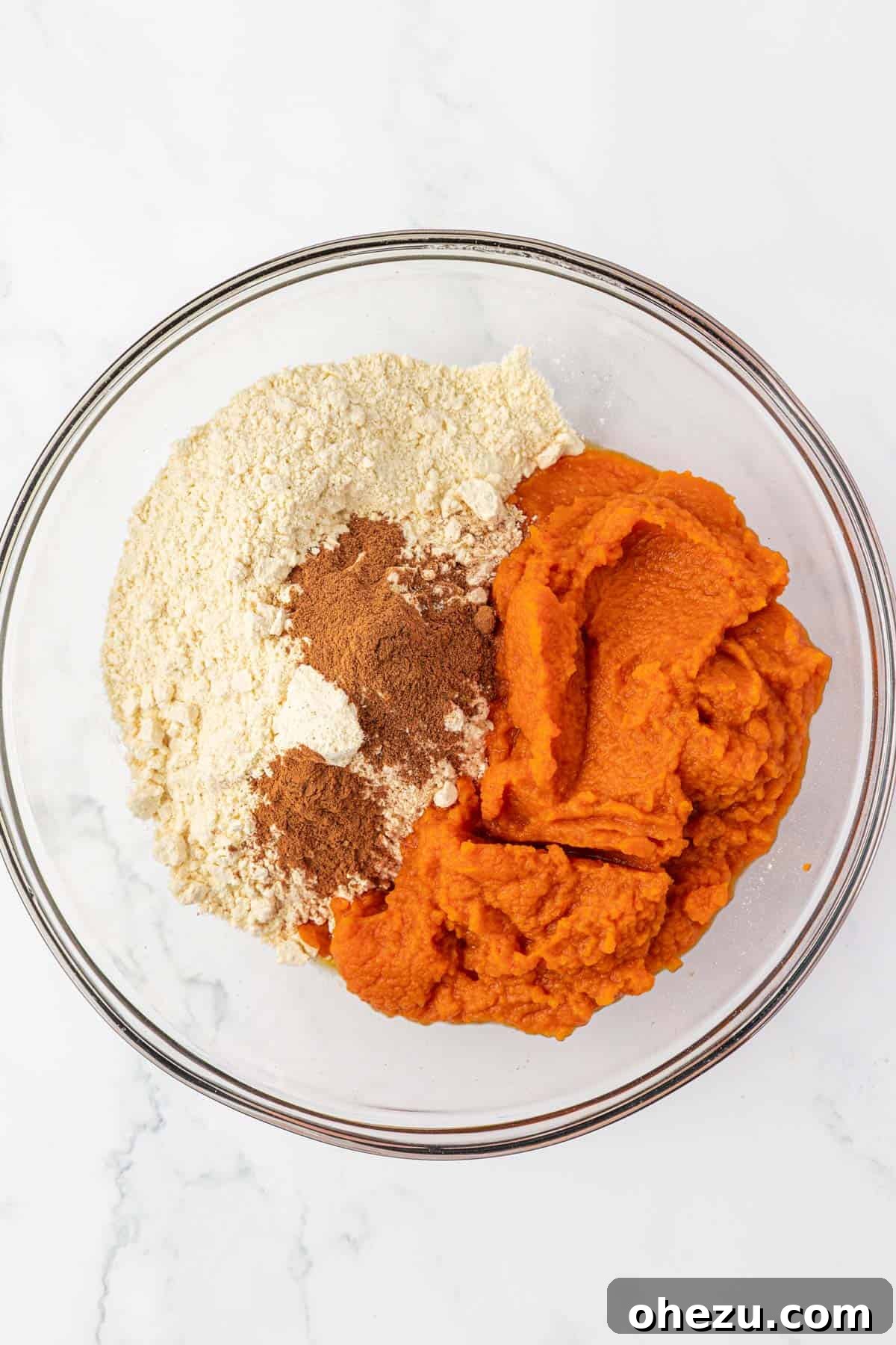 Dry yellow cake mix and canned pumpkin puree in a mixing bowl before combining for pumpkin muffins
