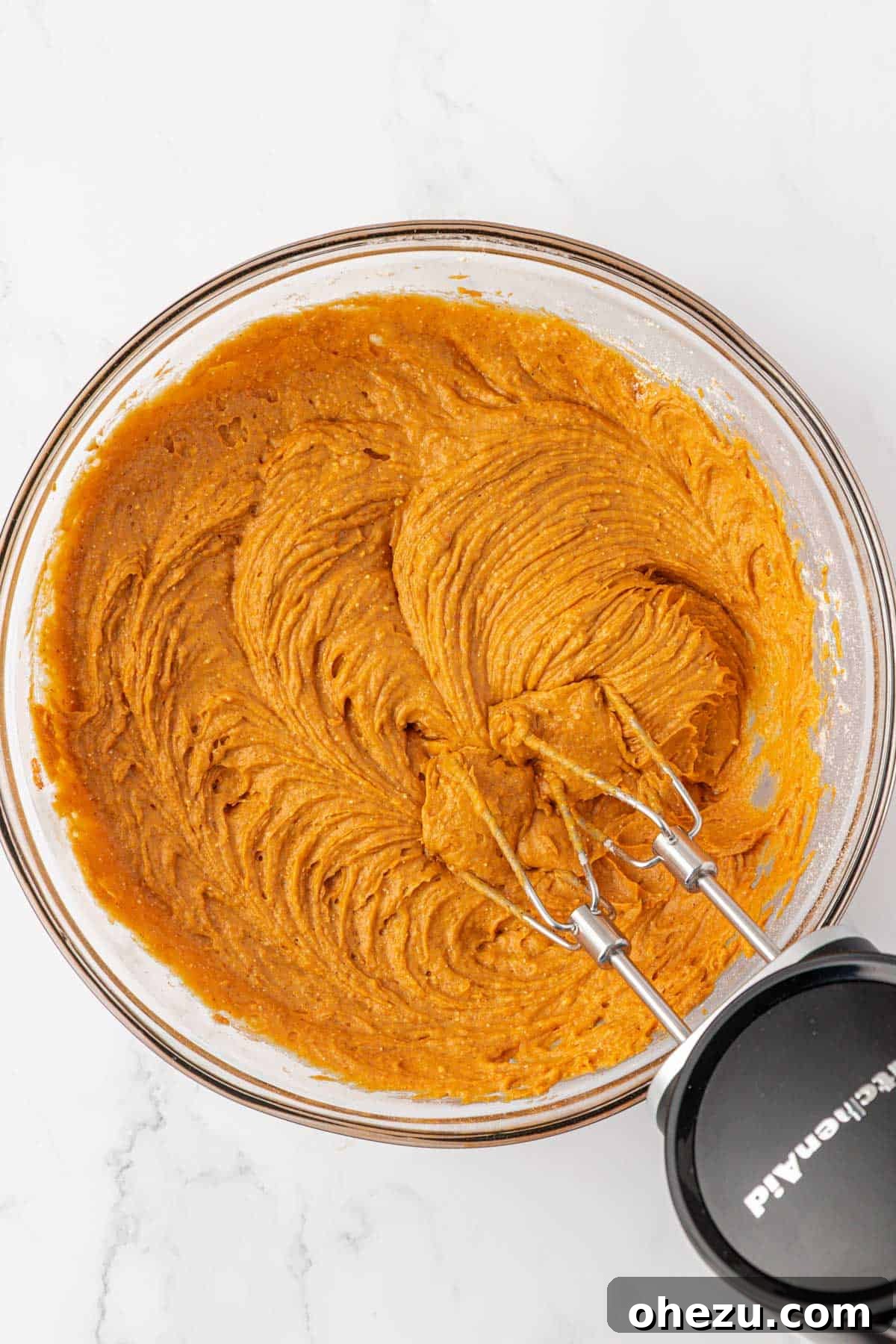 Smooth, orange pumpkin muffin batter mixed together in a bowl, ready for baking