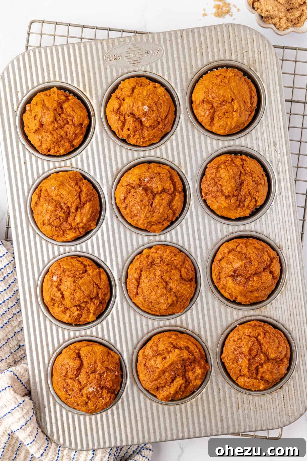 Freshly baked cake mix pumpkin muffins cooling in the muffin tin, golden and puffed
