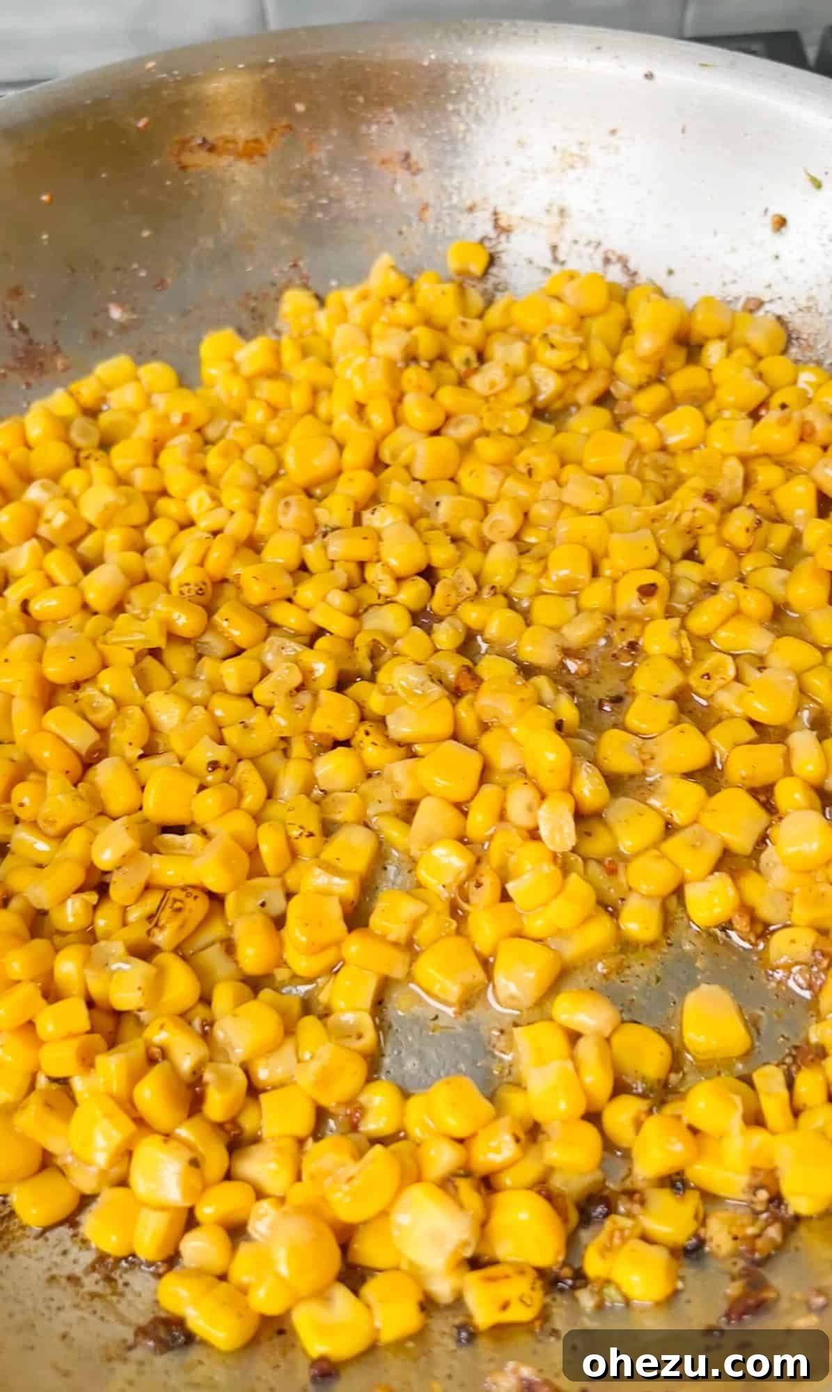 Sweet corn kernels cooking in a skillet, lightly buttered and seasoned.