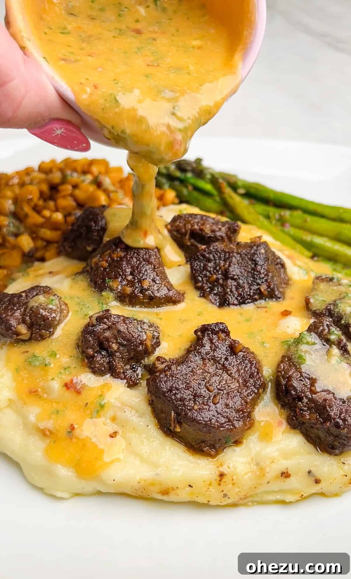 A plated dish of steak bites with mashed potatoes, generously drizzled with golden cowboy butter, capturing the rich texture.