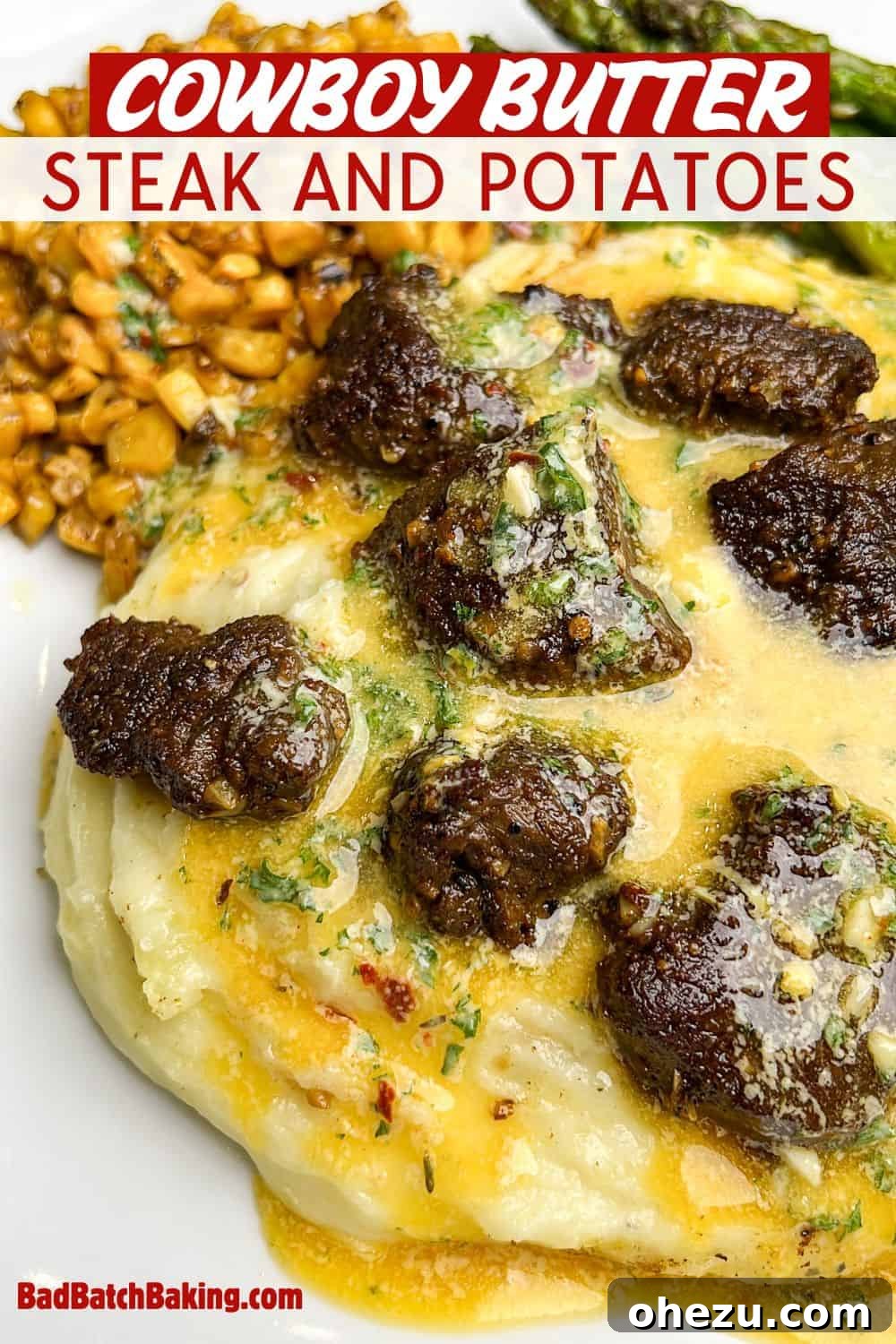 A plated dish of creamy mashed potatoes, seared steak bites, sweet corn, and tender asparagus, all generously coated in cowboy butter, set on a rustic wooden surface.