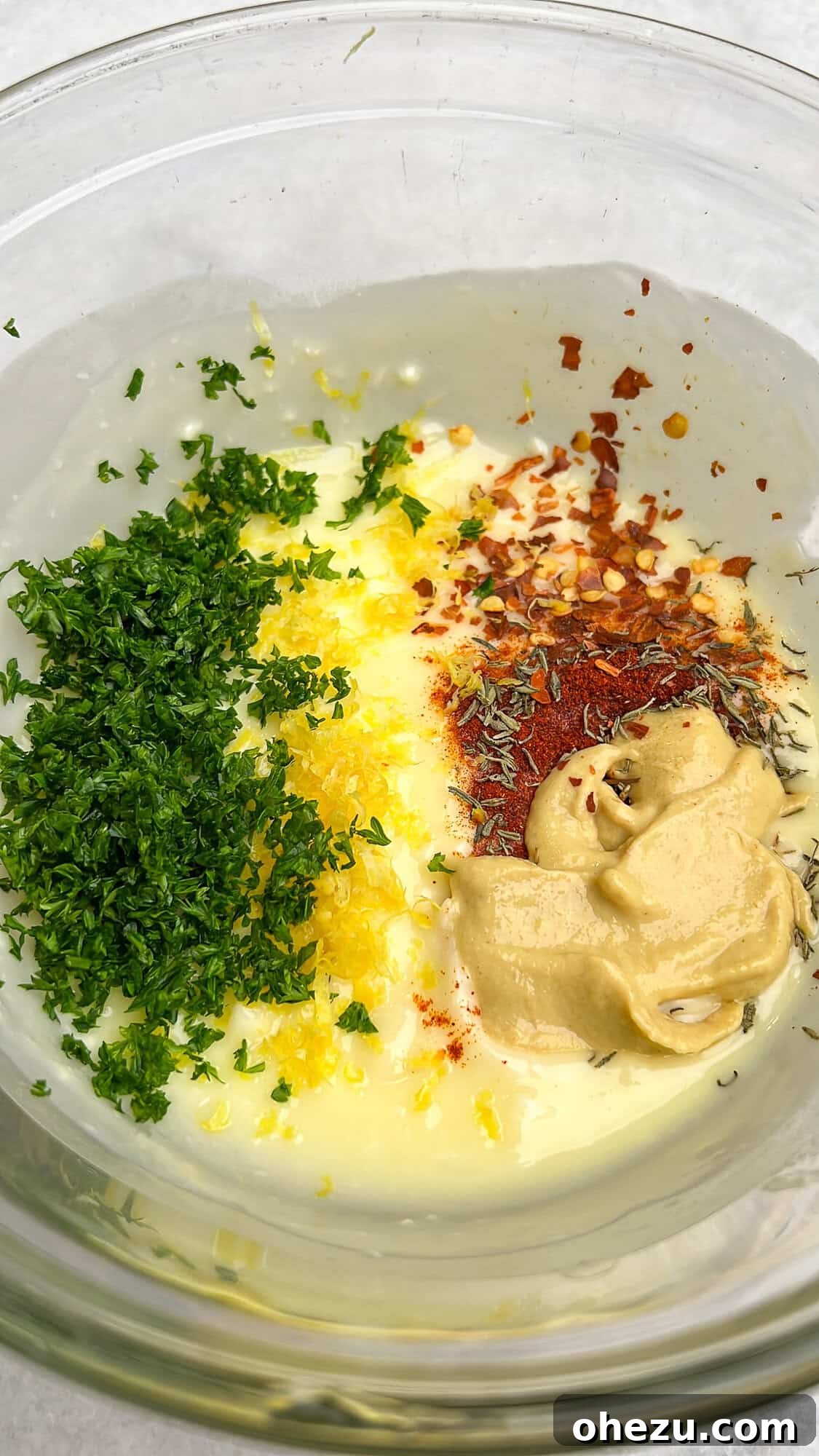 Individual ingredients for cowboy butter arranged in a bowl before mixing, showcasing fresh herbs, lemon, garlic, and spices.