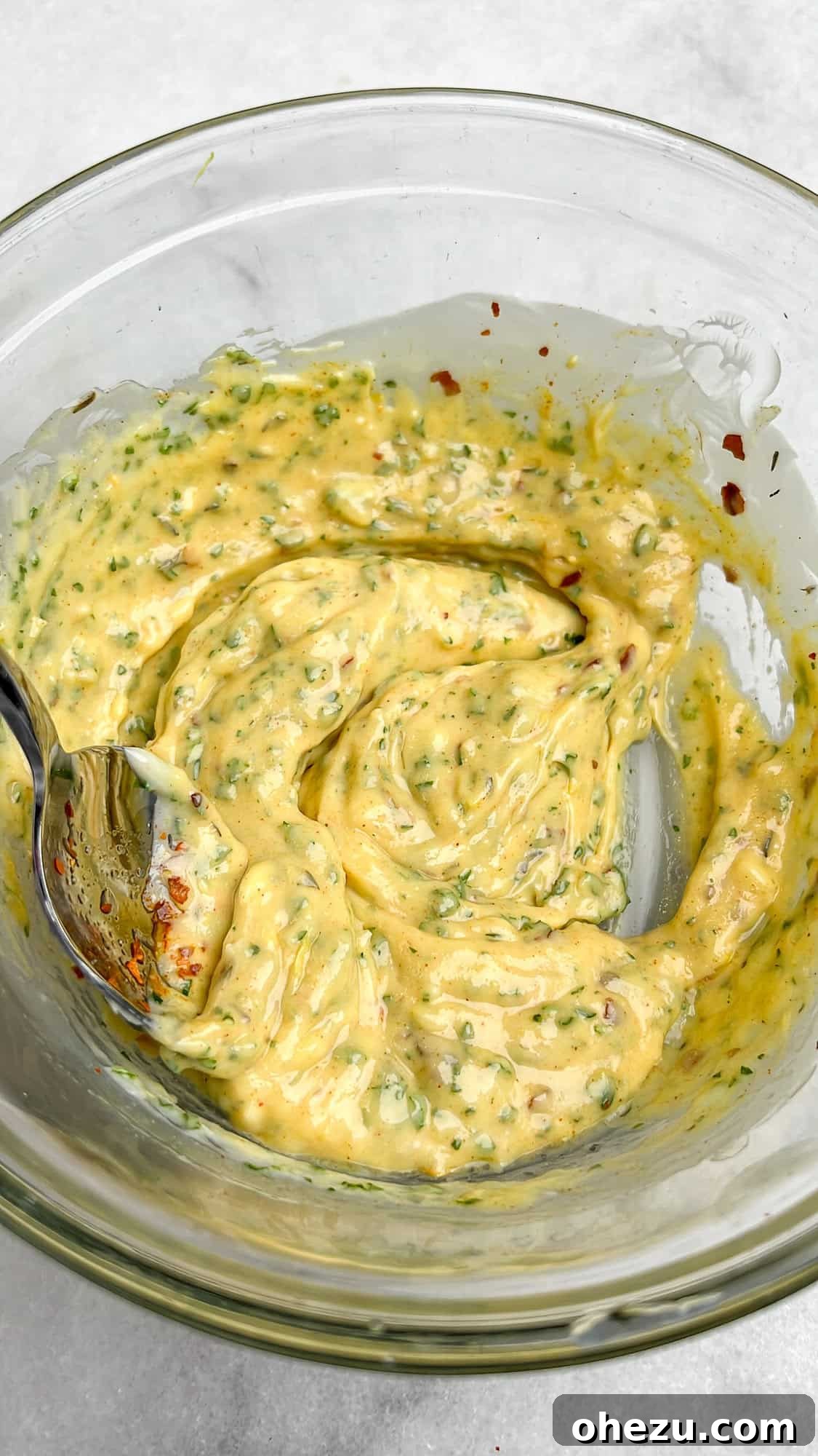 Freshly mixed cowboy butter in a bowl, showcasing its bright color and herb flecks.
