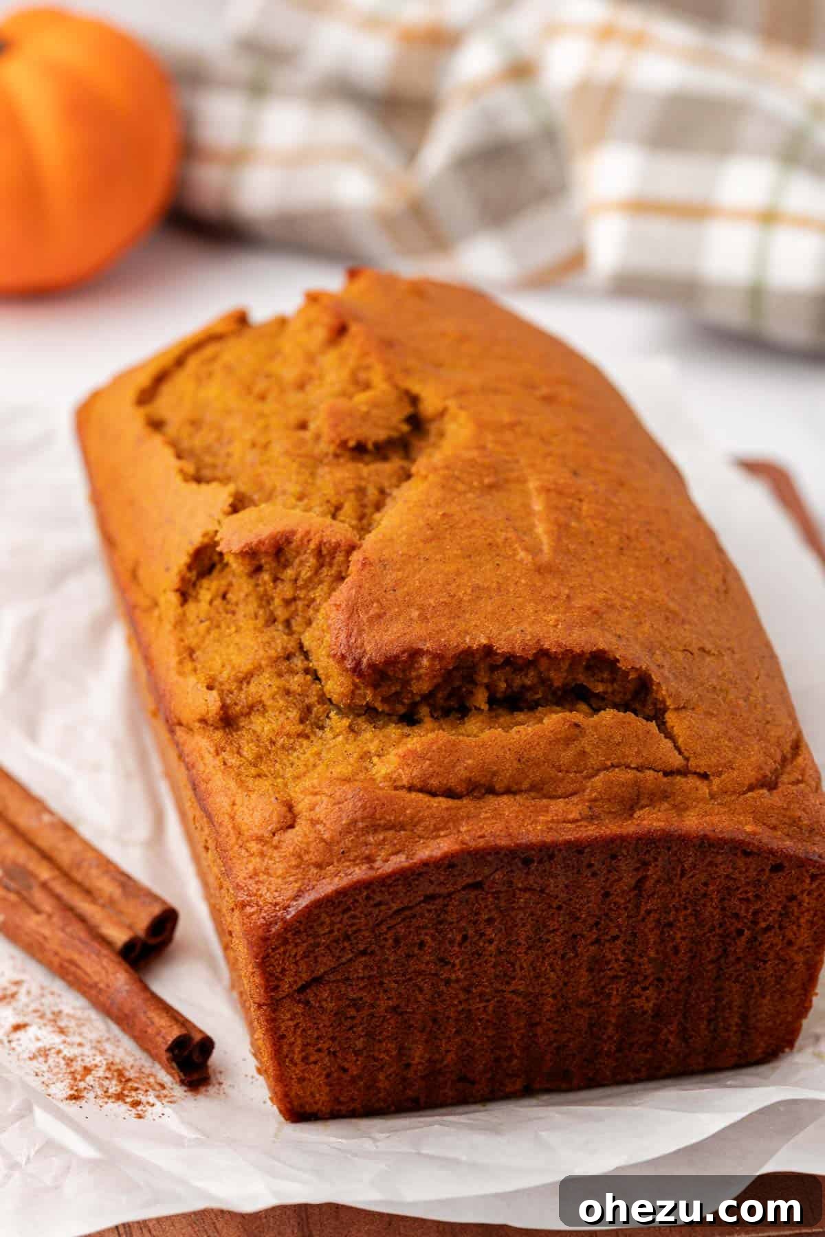 A freshly baked loaf of cake mix pumpkin bread on a cutting board, ready to be sliced.