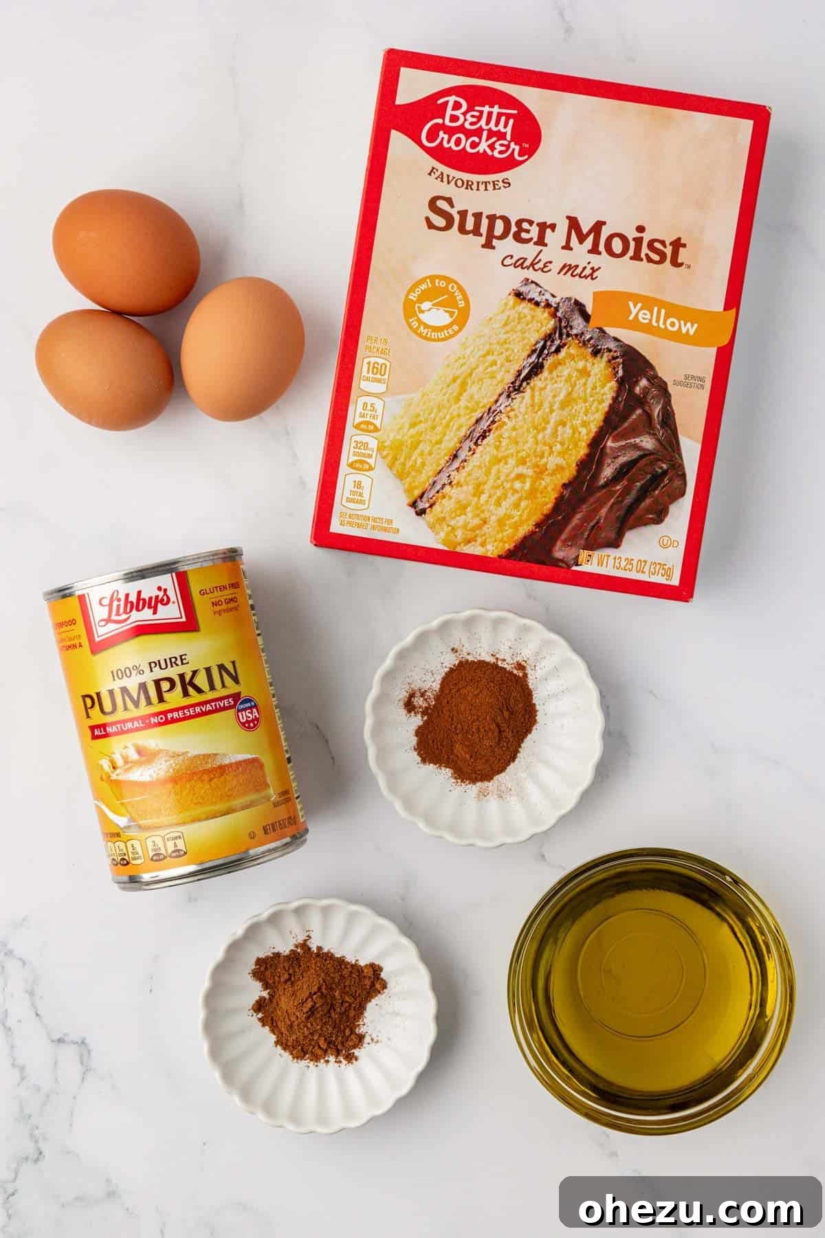 All the essential ingredients for making cake mix pumpkin bread laid out on a counter.