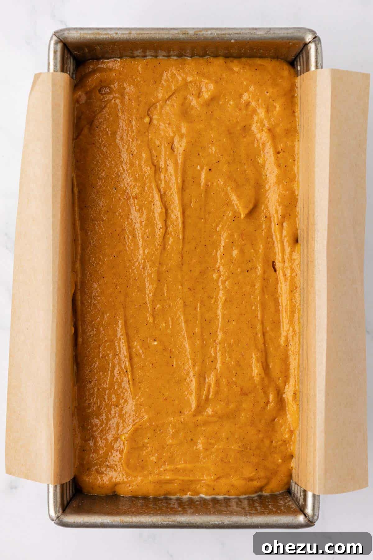 Pumpkin bread batter poured into a loaf pan, ready for baking.