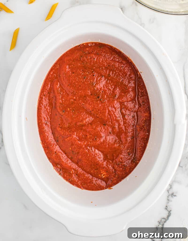 Effortless Slow Cooker Baked Ziti 11 The second layer of rich pasta sauce being added to the slow cooker ziti.