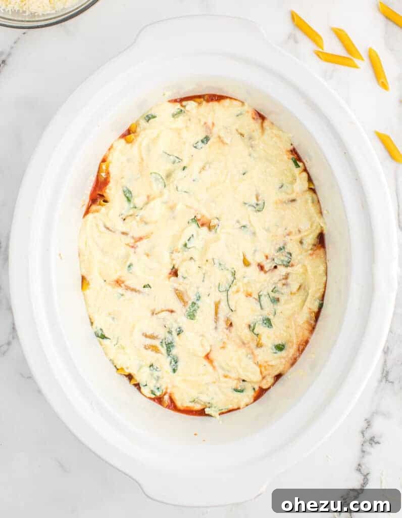 Effortless Slow Cooker Baked Ziti 13 The final ricotta layer being spread smoothly in the slow cooker.
