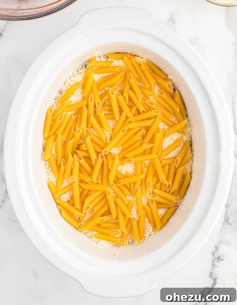 Effortless Slow Cooker Baked Ziti 15 The final layer of uncooked penne pasta added to the crock pot.