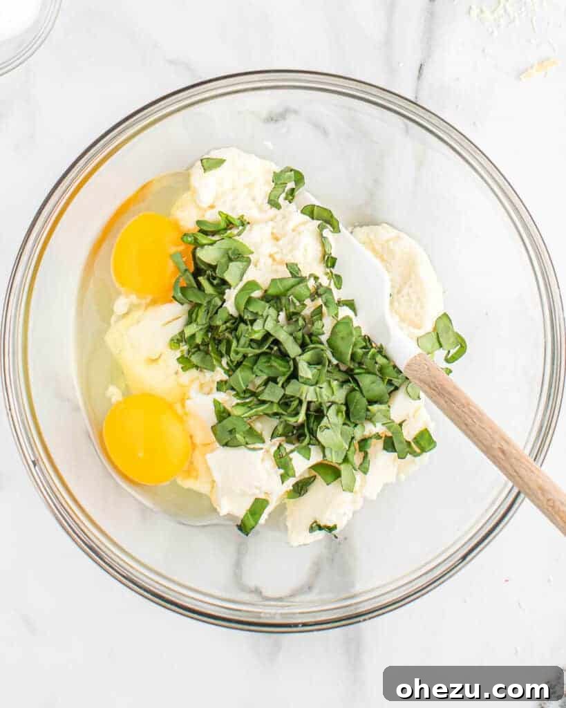 Effortless Slow Cooker Baked Ziti 4 A bowl showing fresh basil, creamy ricotta cheese, and eggs being mixed together for the baked ziti filling.